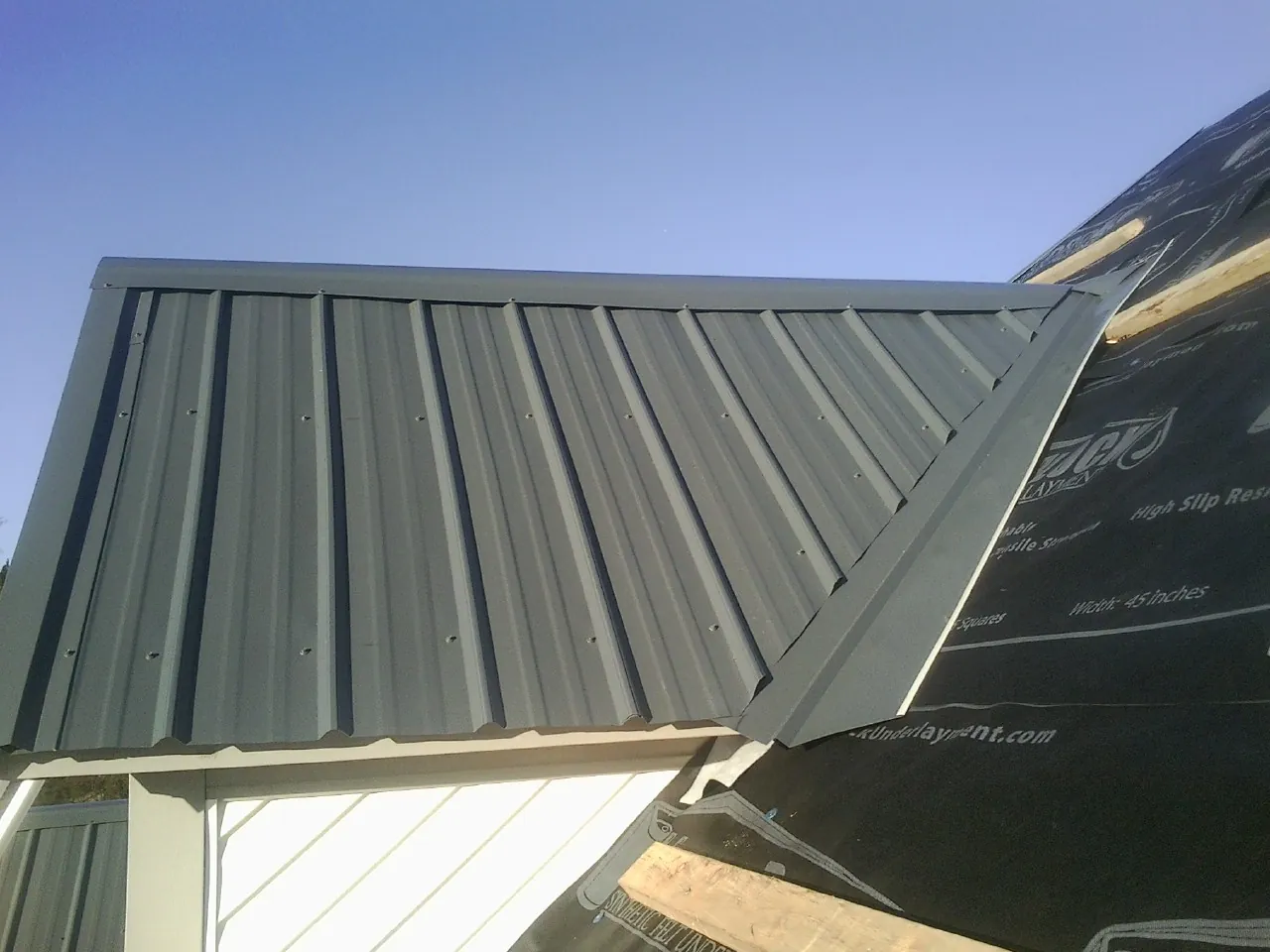 Gray metal roof panels going on over a garage gable in North Babylon