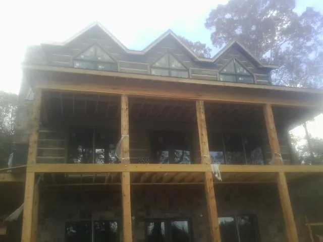 Dormers and porch framing on a large log home under construction — Roof Coating work by our crew in North Babylon