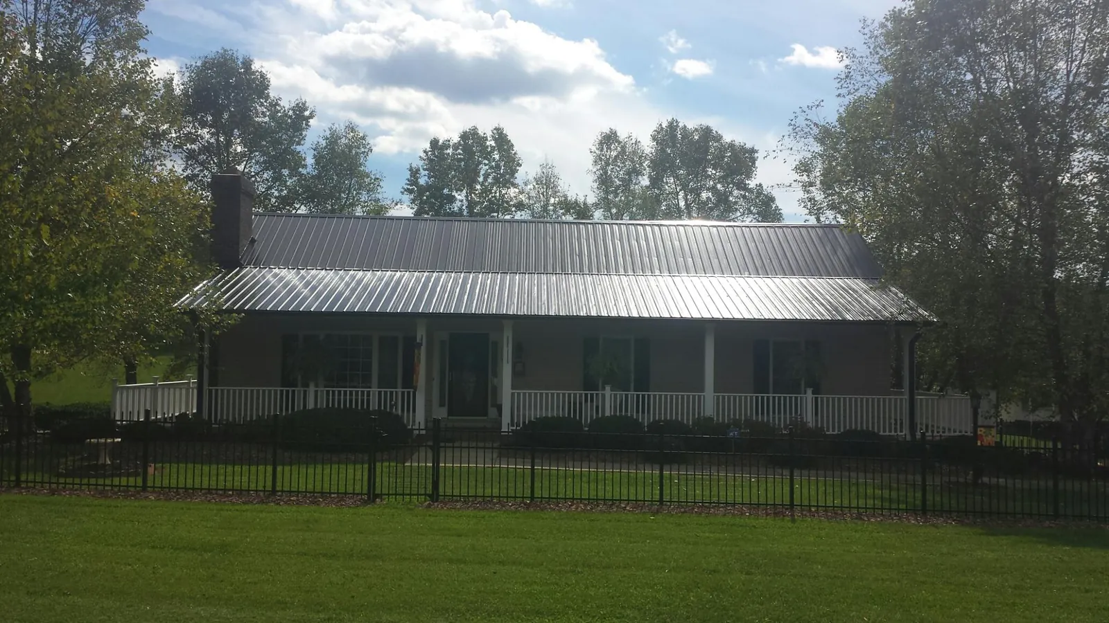 Gray metal roof on a brick ranch with a full width front porch — Gutter Guard Installation work by our crew in North Babylon