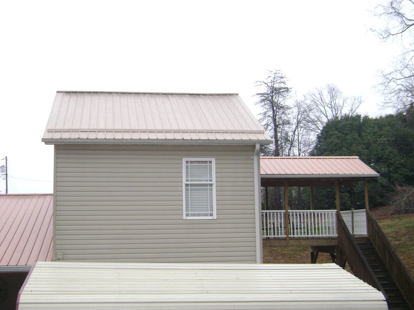 Tan metal roofs on a two story addition and attached porch, from a Roof Replacement job in North Babylon