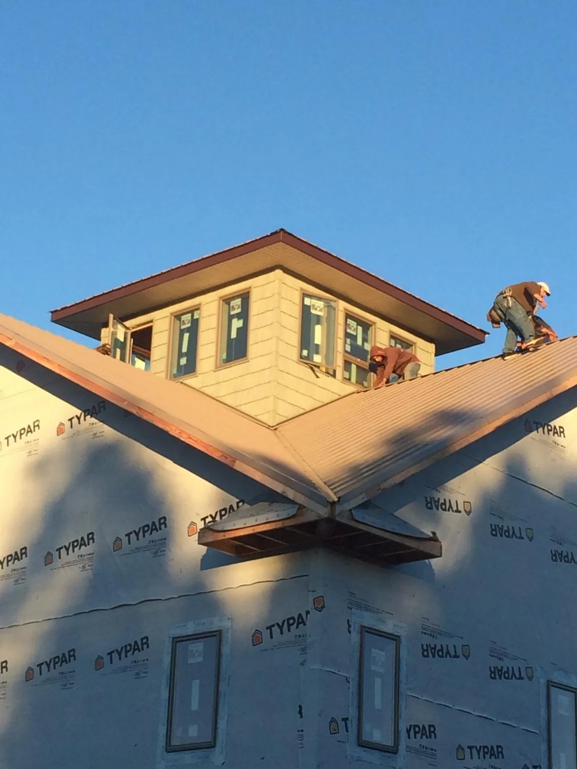 Roofers working around a rooftop cupola on a new metal roof at sunset — Roof Waterproofing in North Babylon by Roofing Brothers